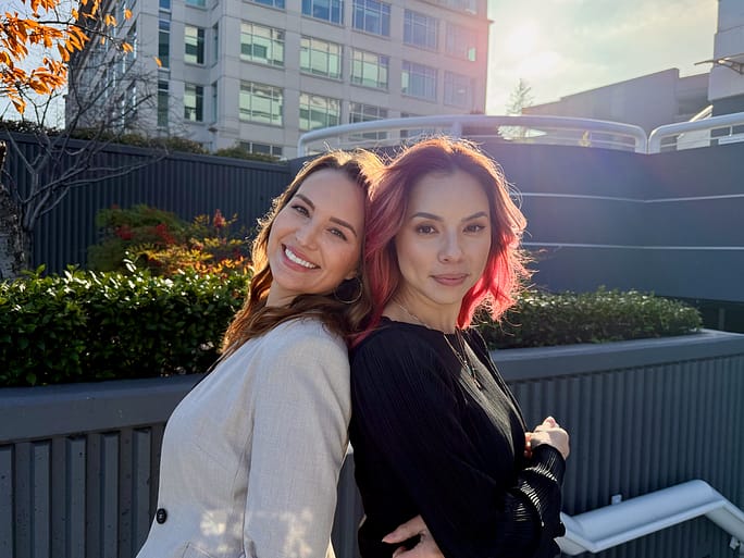 Mandy McEwen and Lindsay Rios, hosts of the Your Future Biz podcast, standing back to back outdoors